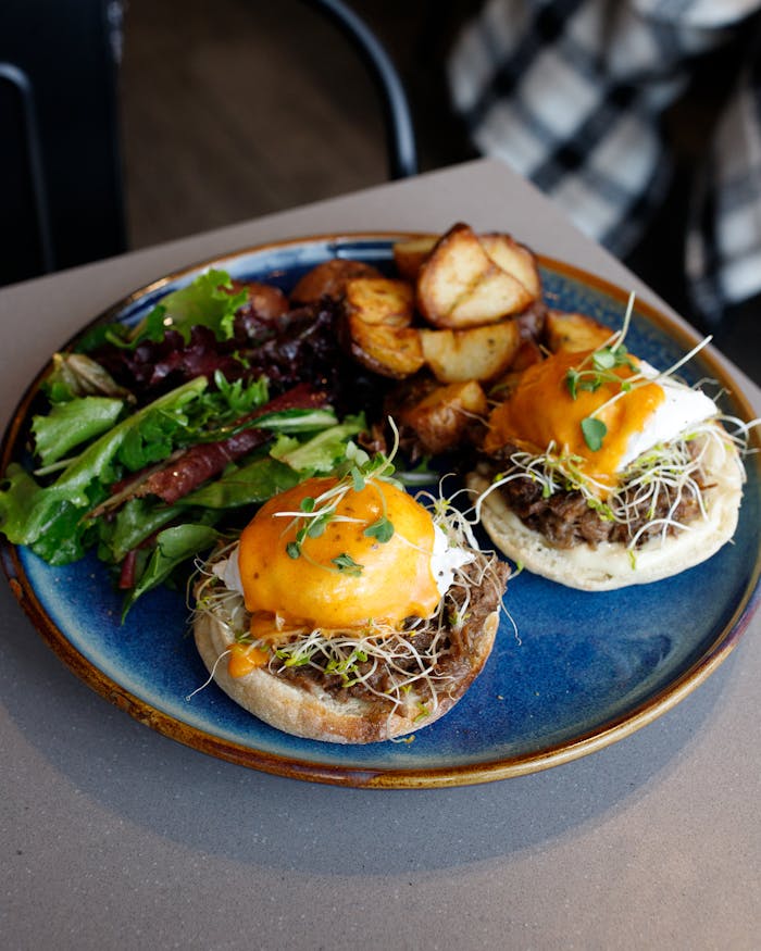 Tasty eggs benedict with melted cheese, sprouts, and mixed greens. Ideal brunch meal.